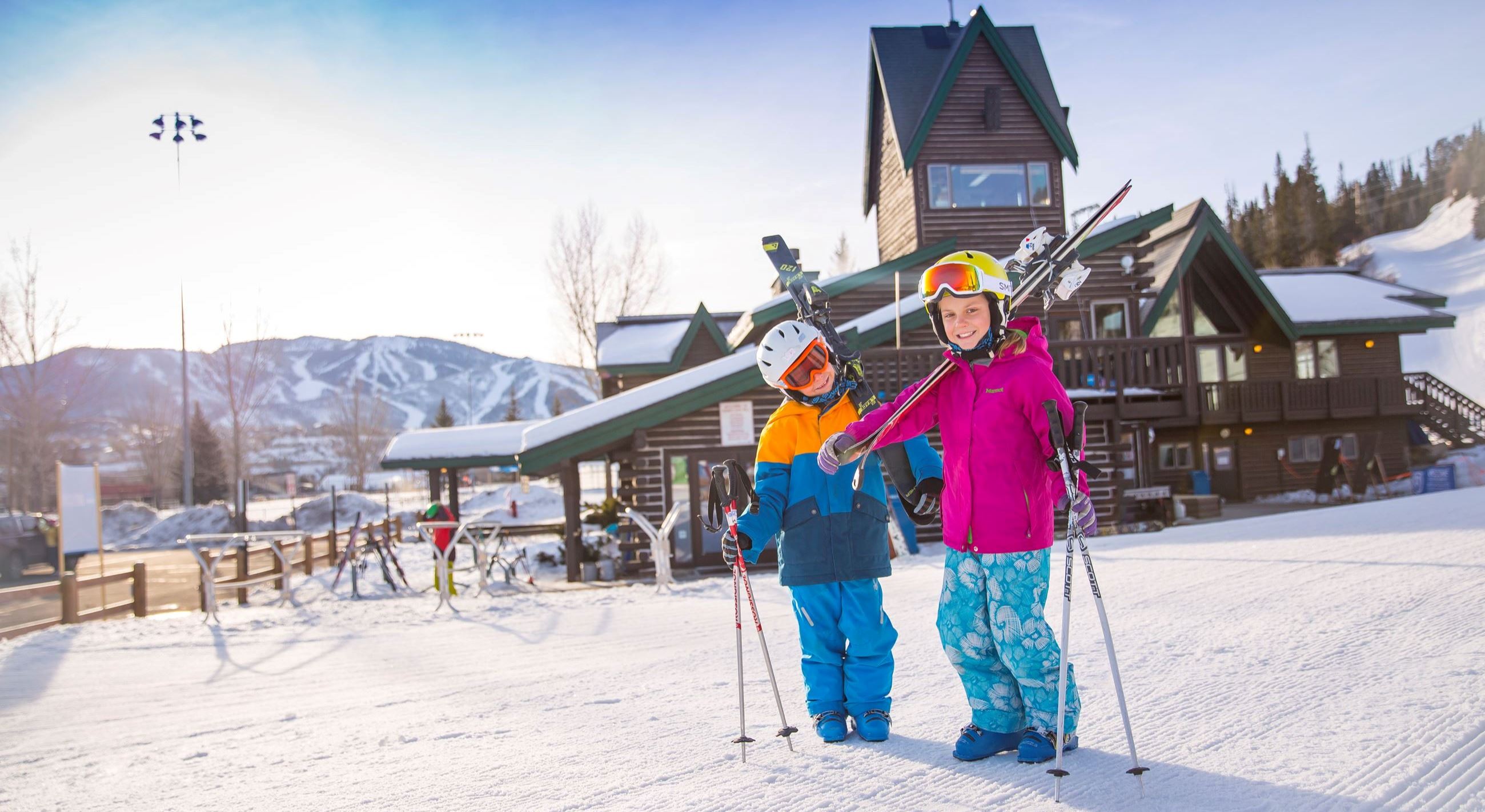 Kids with skis on shoulder at Lodge