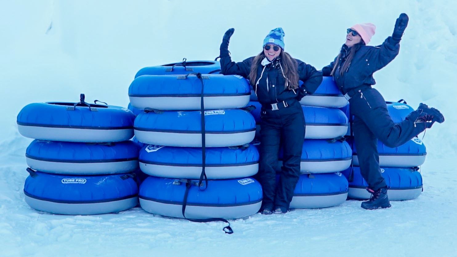 Staff members pose in front of a stack of snow tubes